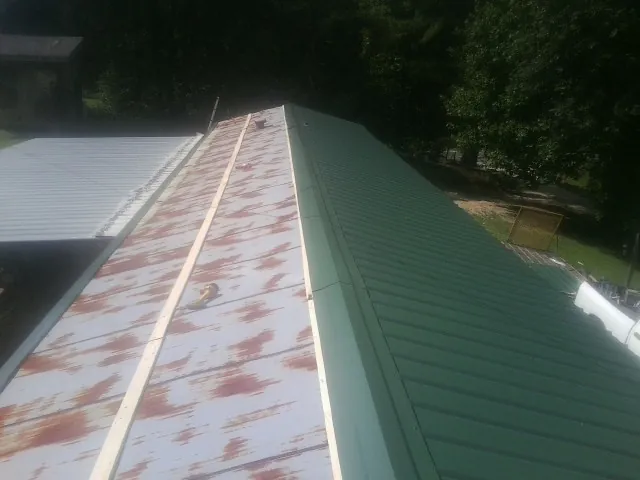 Old rusted panels beside newly installed green metal roofing — Wind Damage Roof Repair by Roofing Brothers in Eagle Lake