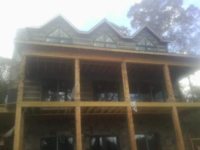 Dormers and porch framing on a large log home under construction — Roof Coating work by our crew in Eagle Lake